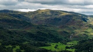 English countryside green grass field and mountain under white clouds during daytime