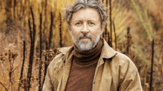 Dan Pearson in his garden, in the autumn with veronicastrum plants behind him.